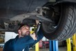© Wavebreak Media - Mechanic examining car tyre using flashlight at the repair garage