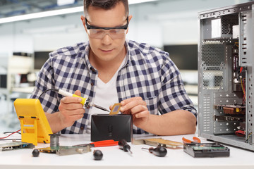 Young PC technician soldering a chip