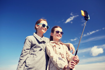 Wall Mural - happy girls with smartphone selfie stick