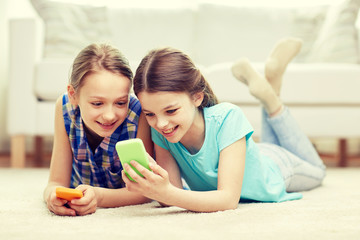 Poster - happy girls with smartphones lying on floor