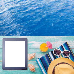 Blank empty tablet computer on beach. Trendy summer accessories on wooden background pool. Sunglasses, orange juice and flip-flops on beach. Tropical flower orchid. Flat mock up for design.