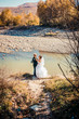 Elegant gentle stylish groom and bride near river with stones. Wedding couple in love