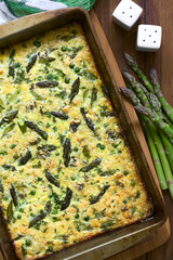 Wall Mural - Frittata made of eggs, green asparagus, pea, blue cheese, parsley and brown rice in baking dish, photographed overhead on dark wood with natural light