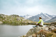 © anrymos - woman sitting on rock and looking at mountain lake