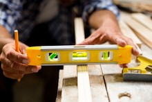 Carpenter Measuring A Length Of Wooden Plank With Spirit Level