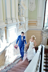 Wall Mural - Wedding couple is walking. Beautiful model girl in white dress. Handsome man in suit. Beauty bride with groom. Female and male portrait. Woman with lace veil. Lady and guy indoors