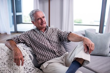 Senior man sitting on sofa in living room