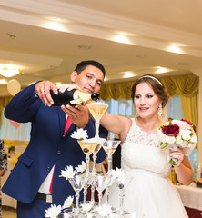 Bride and groom pouring champagne into the glass. 