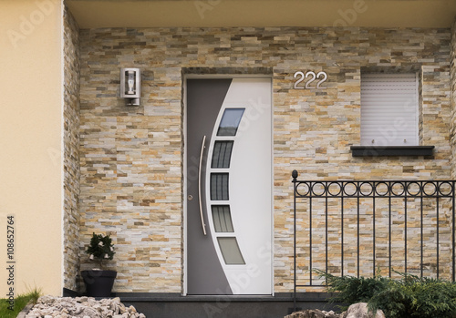 Fotografía Moderner Eingang eines Hauses mit Haustür Fenster Geländer und Verblender aus Sa