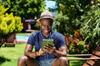 © mimagephotos - Smiling young african man sitting outdoors using digital tablet