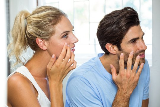 Man and woman applying moisturizer on their face