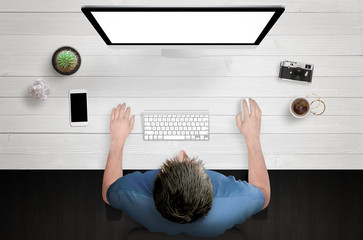 Poster - Man work on computer with white isolated screen. Work desk with plant, camera, coffee, smart phone. Top view.