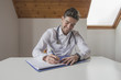 © GENETTICA - Smiling doctor writing a report in his office. He is sitting at