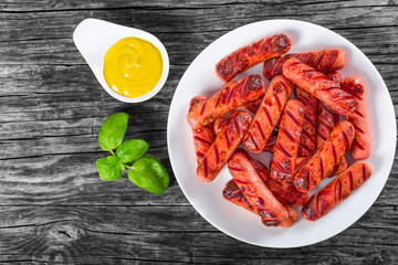 Poster - Grilled sausages on a white dish, top view