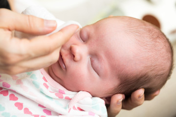 Wall Mural - Mother cleaning eyes of a newborn baby with physiological soluti