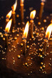 Black round birthday cake with burning golden candles on white b