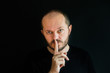 © ilijaa - Serious man with beard and mustaches on black background in low key, making silence gesture, pst, shh