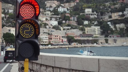 Poster - Stop red signal  at a traffic light. Mediterranean city view.  Boat along shore. Area close to the seaside with cars on the road.
