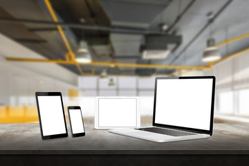 Wall Mural - Laptop, tablet and smart phone responsive display devices on table. Isolated white screen for mockup presentation. Office interior in background