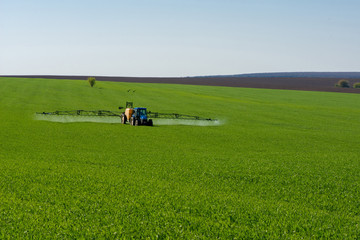 Tractor spraying pesticide in a field of wheat