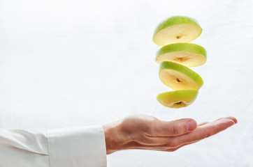 Wall Mural - Men's hands hold the flying pieces of apple