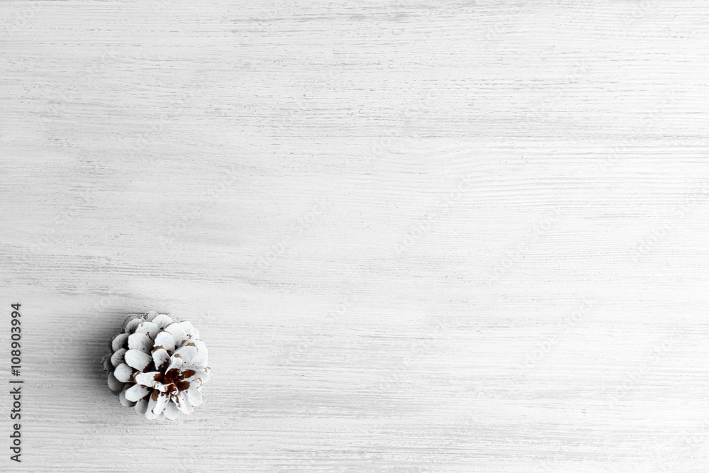 Beautiful simple winter background with pine cone on wooden texture