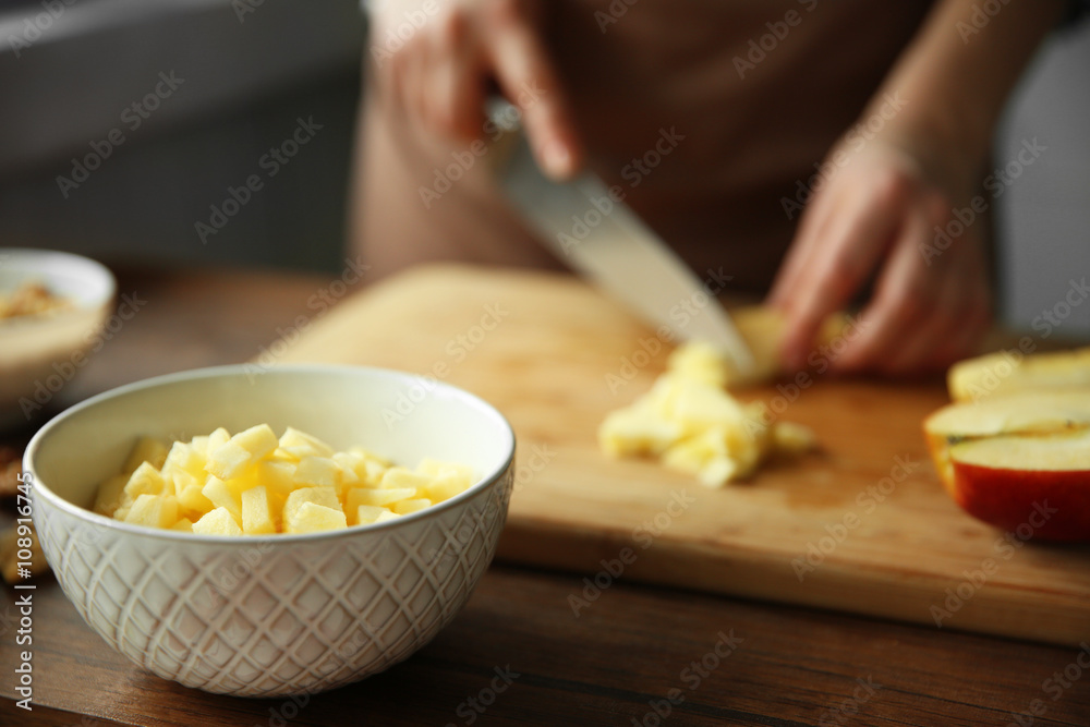 Woman chopping ripe apple on a cutting board