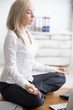 © fizkes - Business woman sitting in padmasana pose