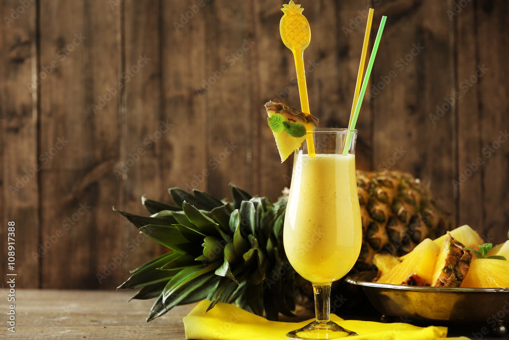 Pineapple smoothie in cocktail glass on wooden background