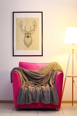 Wall Mural - Pink armchair with blanket and lamp on light wall background