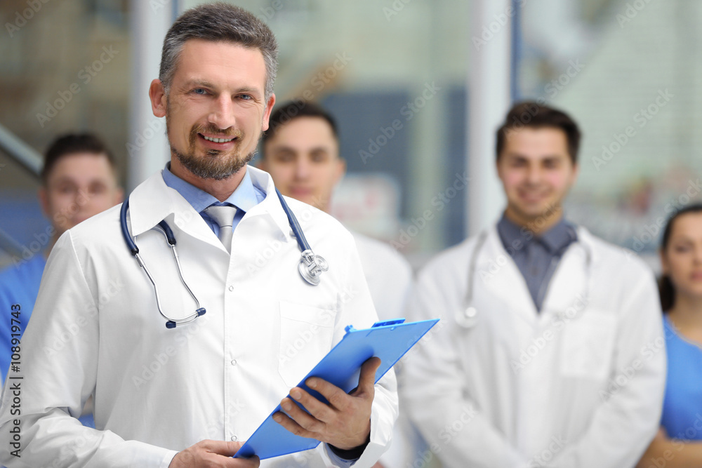Smiling doctor with medical workers standing in hospital