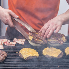 Wall Mural - Chef making beef burgers outdoor on open kitchen international food festival event. Street food ready to serve on a food stall.