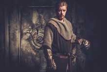 Young Medieval Knight Standing On Dark Background.