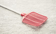 Fly swatter on stone table. Concept of exterminating bugs and insects.