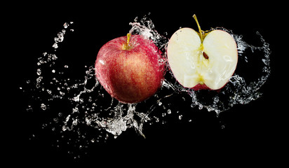 Red apples in water splash over black background