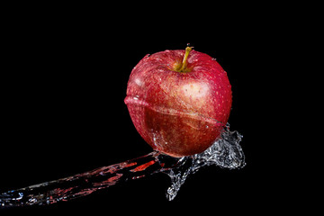 Wall Mural - Red apple in water splash against black background