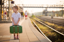 Adorable Little Kid Boy Dressed In Shorts And Polo T-shirt On A Railway Station, Waiting For The Train With Retro Old Green Suitcase. Ready For Vacation. Young Traveller On The Platform.