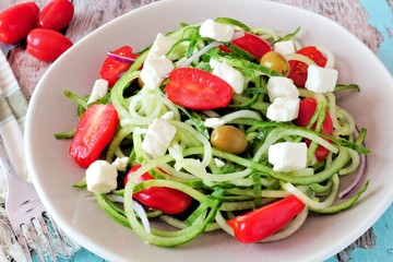 Wall Mural - Fresh Greek Salad with cucumber noodles close up on vintage plate