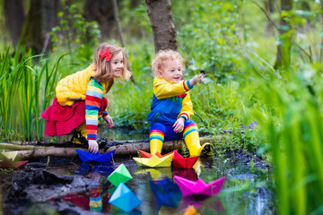 Kids playing with colorful paper boats in a park