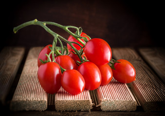 Tomatoes branch on rustic wooden table dark background