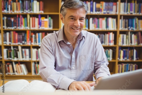 Fotomural Portrait of happy professor sitting at desk using laptop