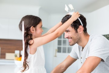 Wall Mural - Smiling daughter wearing butterfly headband to father 