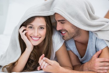 Wall Mural - Smiling couple lying under blanket 