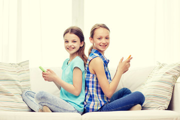 Wall Mural - happy girls with smartphones sitting on sofa