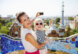Smiling mother and baby taking photos with camera at Park Guell