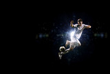 Fototapeta Sport - Soccer player in action over black background