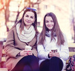 © byswat - Mother and daughter sitting in autumn or spring park bench, are kept the hands of cups coffee