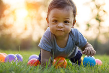 Cute Asian Baby Crawling In The Green Grass And Colorful Ball