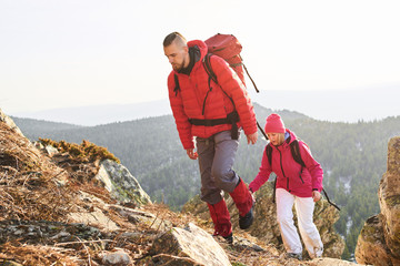 A group of tourists, consisting of a guy and a girl, rises to the top of the mountain