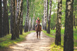 Молодая девушка катается верхом на лошади в  березовом лесу летом